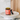 An amber glass jar of North Hound Life Immune Support + 100% turkey tail powder with its black lid resting beside it on a white pedestal, set against a background of a wooden cutting board and marble surface.